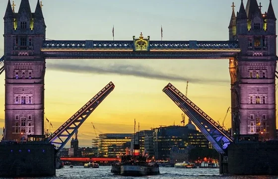 Wide shot of London's Tower Bridge across the Thames with a traveler in the foreground on a bright clear day