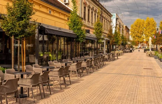 Empty European street cafe in early spring with bare budding trees and soft morning light on stone buildings