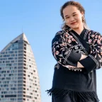 Solo female traveler at a city viewpoint looking confidently at a panoramic cityscape