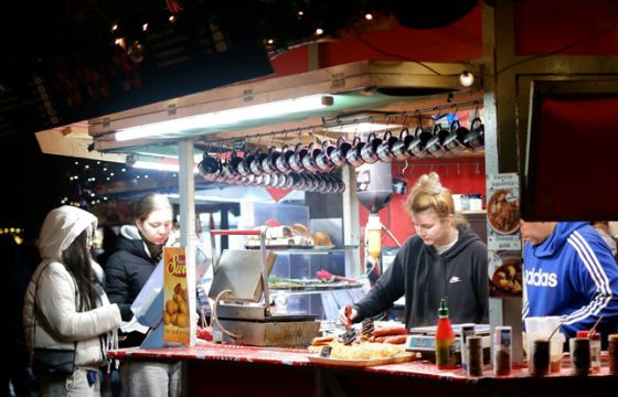 Traveler at a small outdoor food stall waiting to enjoying a local meal at a busy market food stall