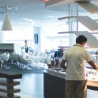 Traveler relaxing in a plush seat in a calm airport lounge with a buffet food spread and drinks bar visible