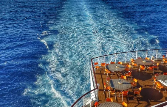 Cruise ship deck with empty lounge chairs overlooking the open turquoise ocean on a bright sunny day