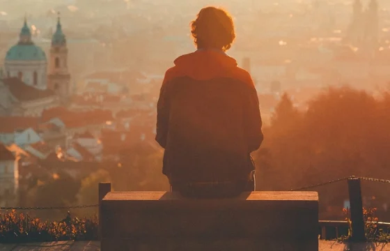 Solo traveler with a dramatic scenic overlook of a European city stretching into the distance